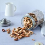 A glass jar on it's side and granola falling out on the table from the jar.