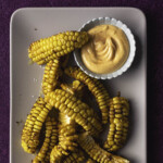 Maissiribsejä lautasella. Lautasella on pieni dippikulho, jossa on sriracha-majoneesia.