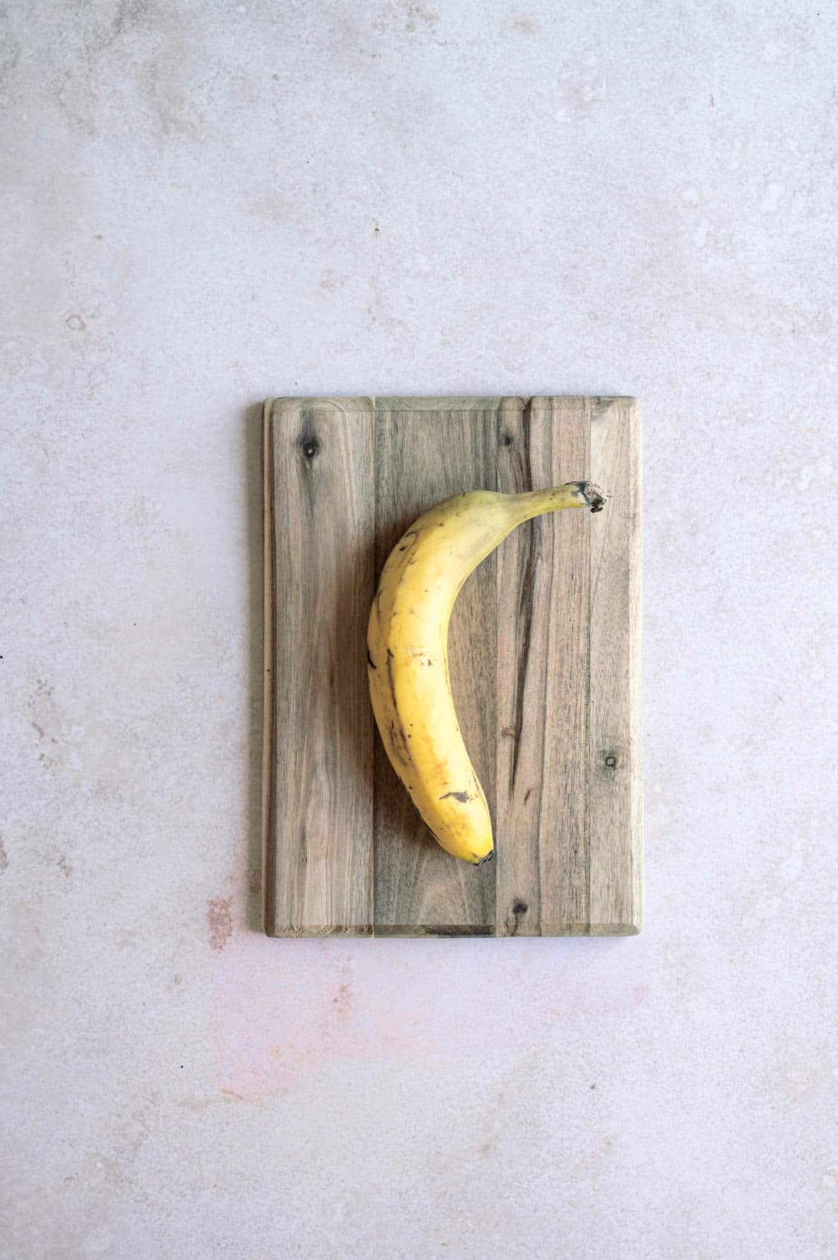 Kokonainen banaani puisella leikkuulaudalla.